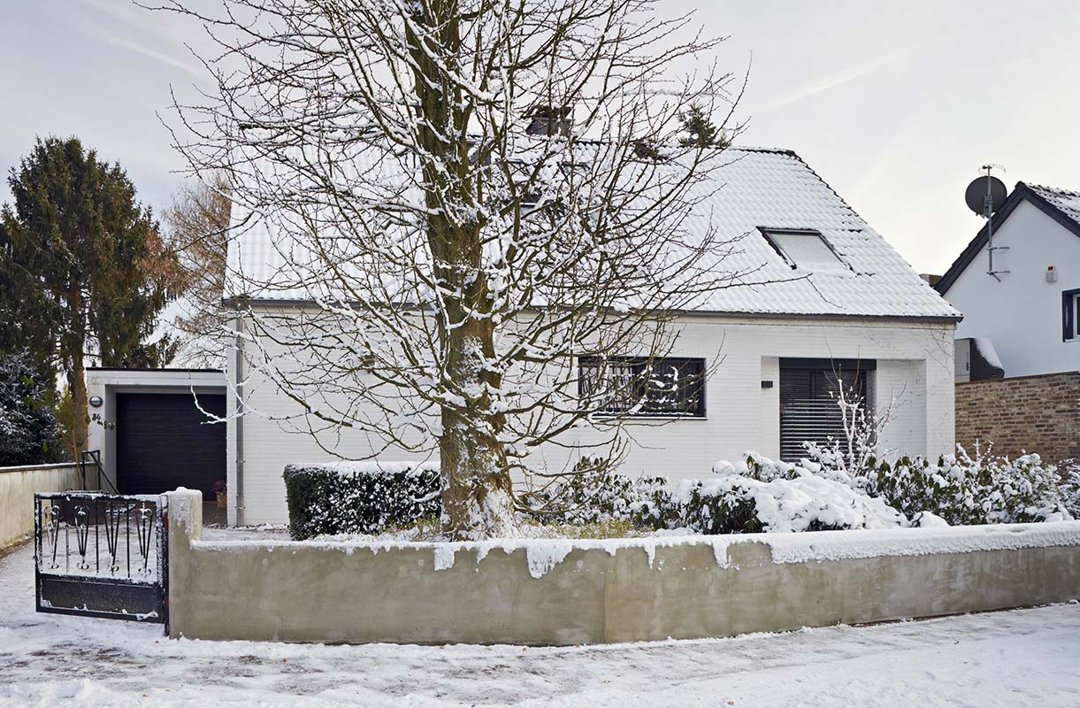 Einfamilienhaus in Düsseldorf Kalkum mit einem Baum im Vorgarten im Winter.