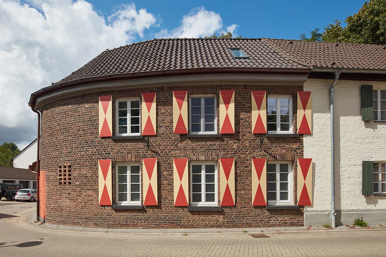 Die Backsteinfassade mit historisch zweifarbigen Fensterläden.